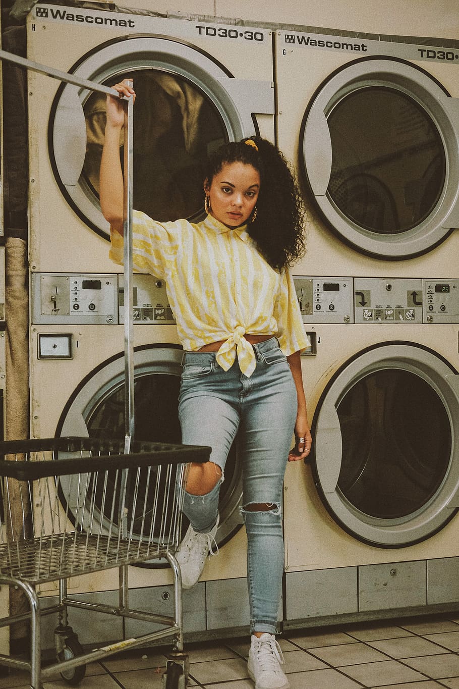 woman wearing distressed blue jeans, woman standing beside front-load washer and dryer