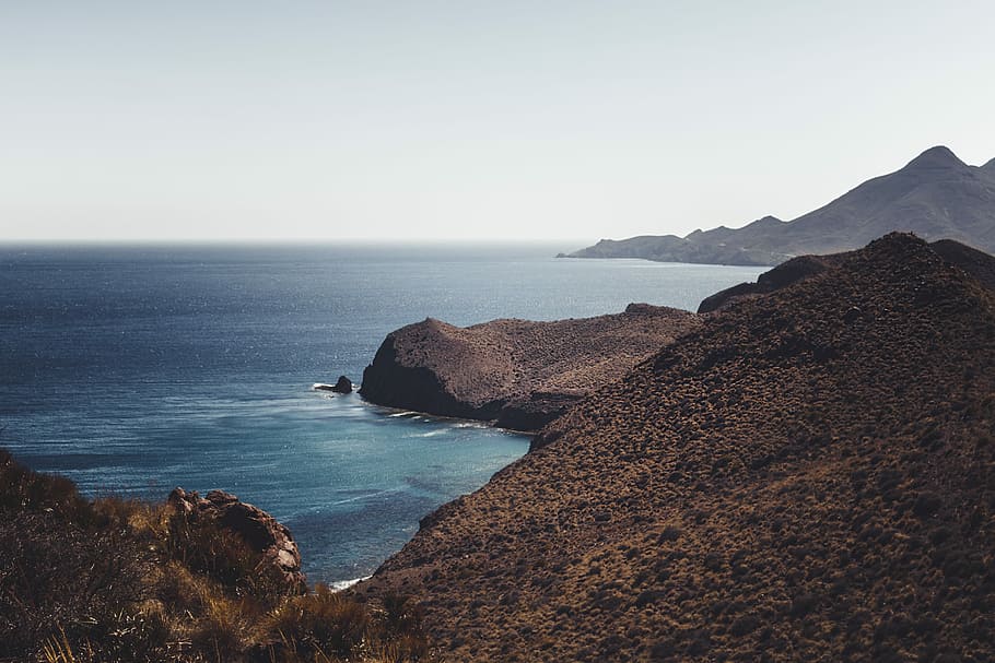 sea on foot of mountain, blue, brown, coast, gray, rocks, nature HD wallpaper