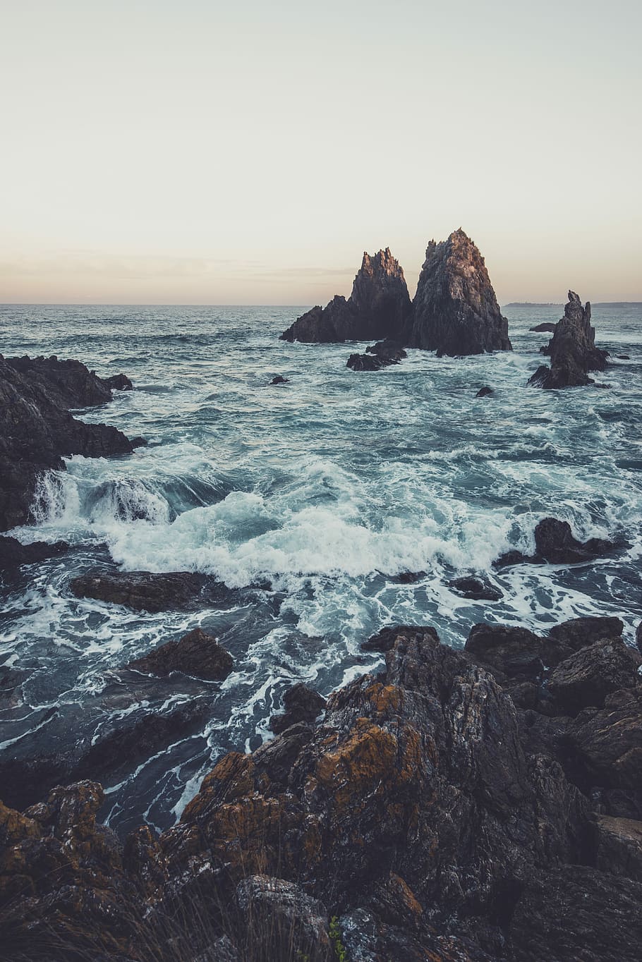 rock formations in ocean under blue sky during daytime, waves crushing the rocks HD wallpaper