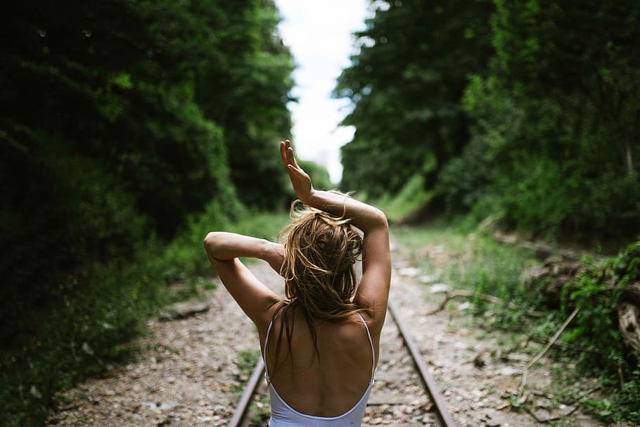 woman stand in train rail, woman in the middle of rail road lifting her hands up HD wallpaper