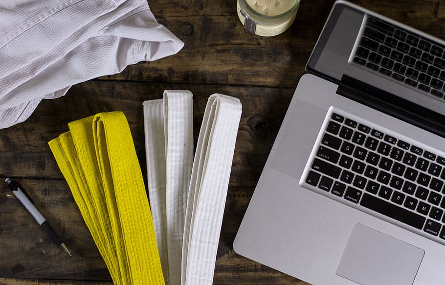yellow and white Karate Gi belts beside MacBook Pro on top of table