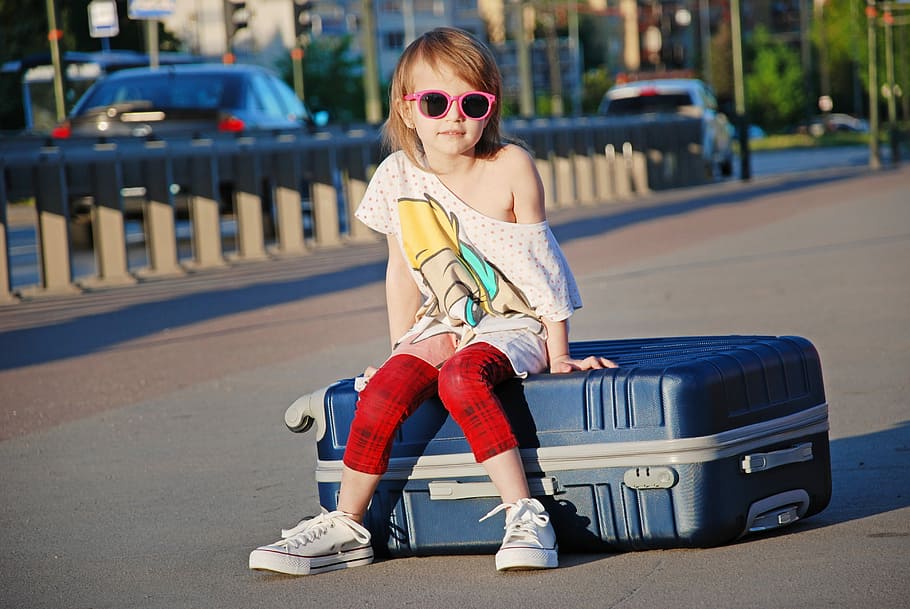 woman sitting on black luggage bag, street, city, suitcase, child