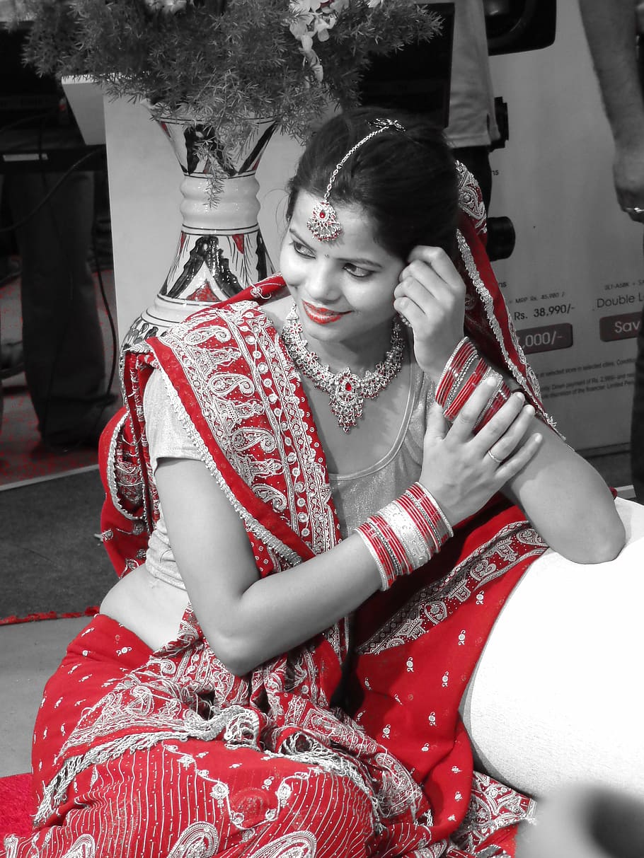 woman in red floral saree dress sitting on the sofa smiling HD wallpaper