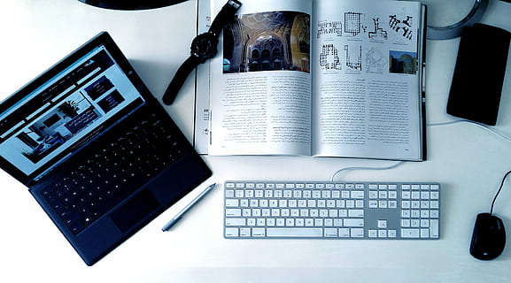 laptop beside book with watch on top next to corded keyboard and computer mouse HD wallpaper