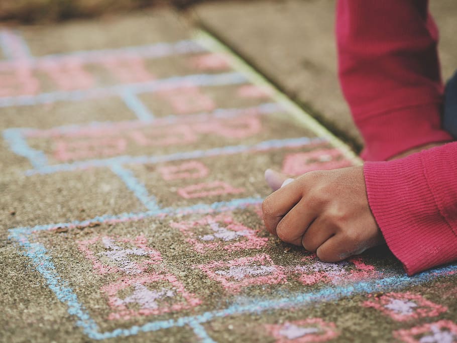 person holding chalk lying on concrete surface, person writing on brown concrete pavement HD wallpaper