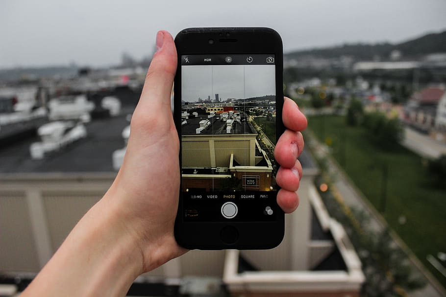 person holding iPhone showing building rooftop, apple, city HD wallpaper