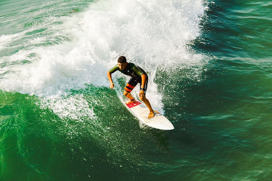 man on surfboard surfing against waves, man rides on white surfboard during daytime HD wallpaper