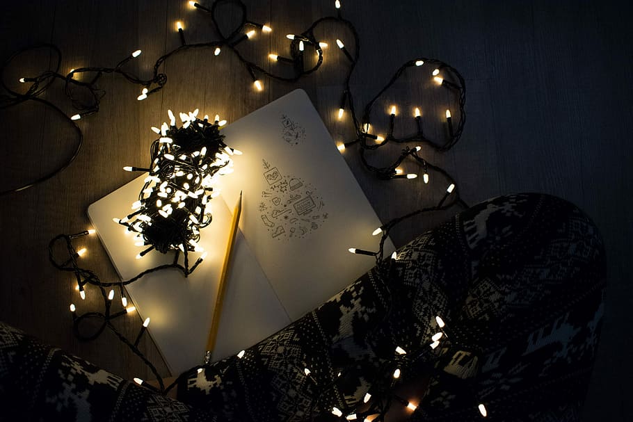 photo of string lights on open book beside pencil, turned on string lights on book