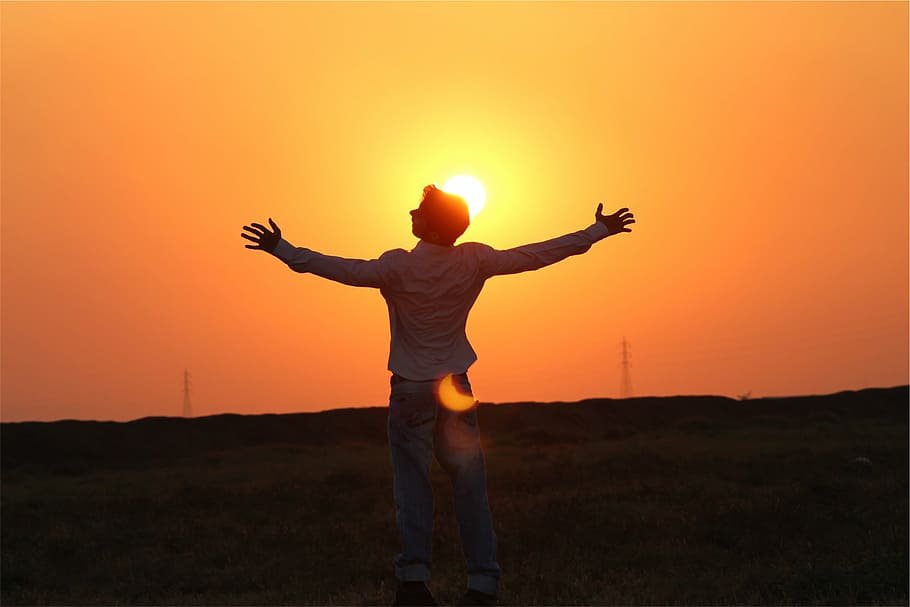 man in white dress shirt standing on green grass field during sunset HD wallpaper