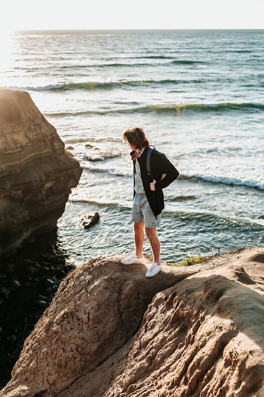 person standing on rock near sea, man standing on rock formation near sea HD wallpaper