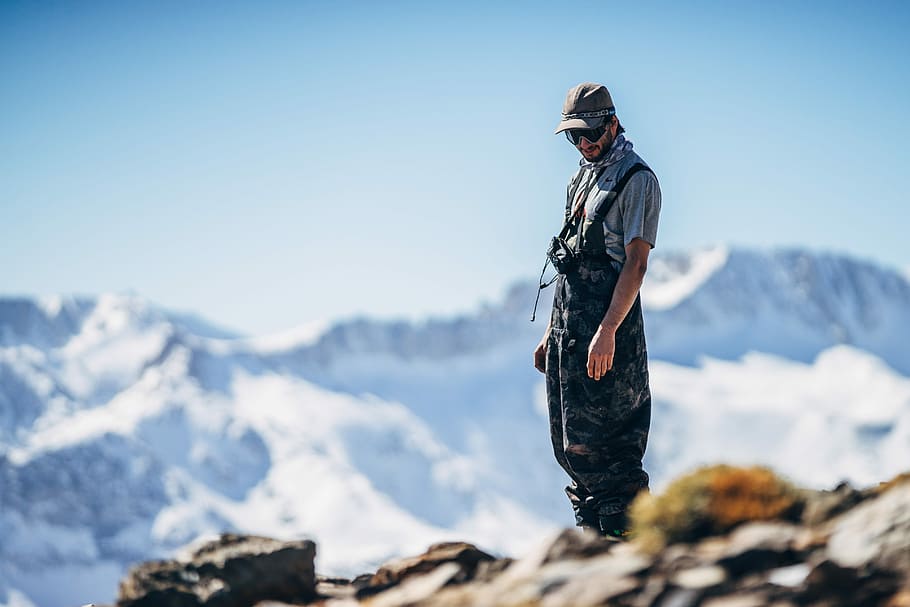 man standing on cliff during daytime, man standing on mountain top HD wallpaper