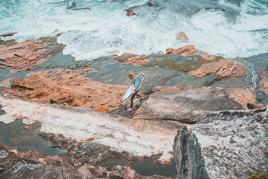 person holding surfboard on seashore, person holding surfboard walking on shore at daytime HD wallpaper