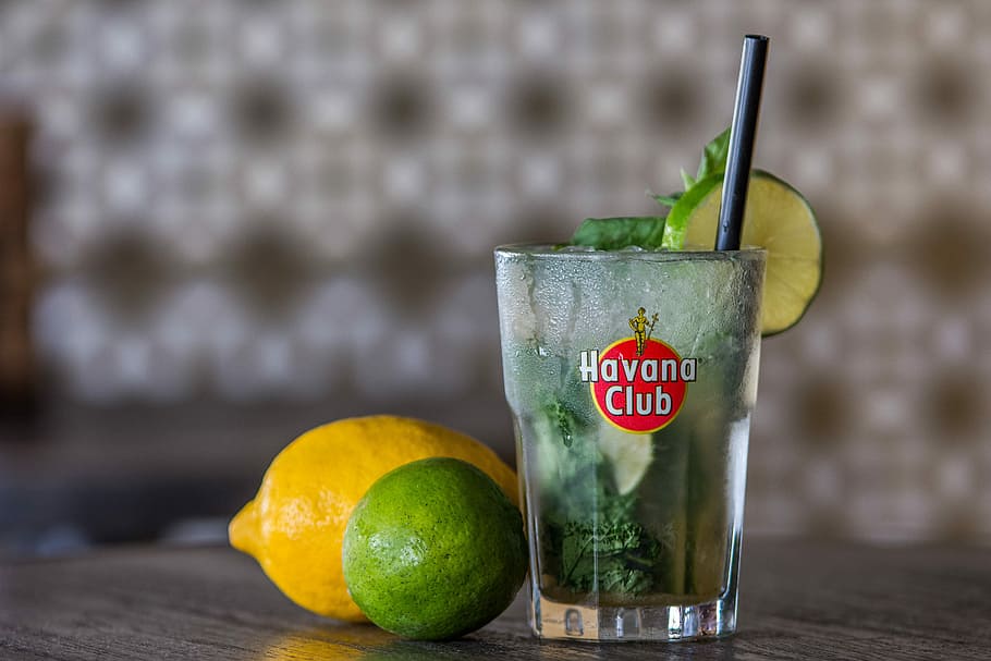 Havana Club drinking glass with lemon and lime on table, Mojito