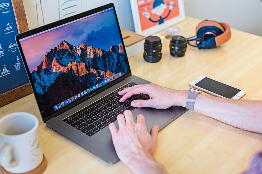 MacBook Pro turned on beside white ceramic mug, person wearing silver Apple Watch using MacBook Pro, HD wallpaper