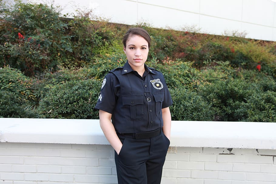 woman police officer standing near green plants, bodyworn, body camera