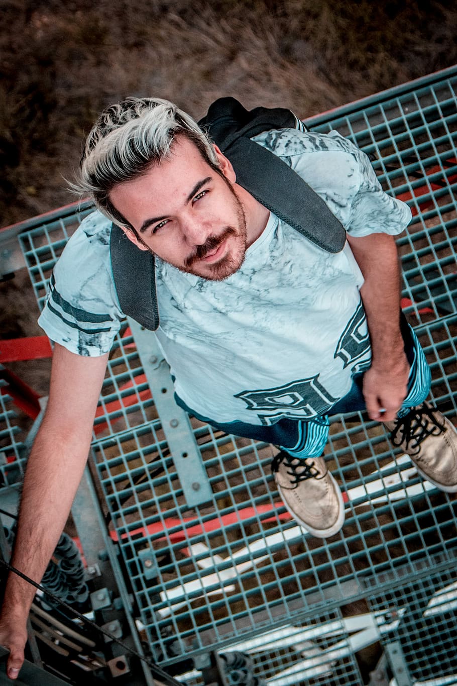 man standing on tower looking up, man standing on blue mesh surface HD wallpaper