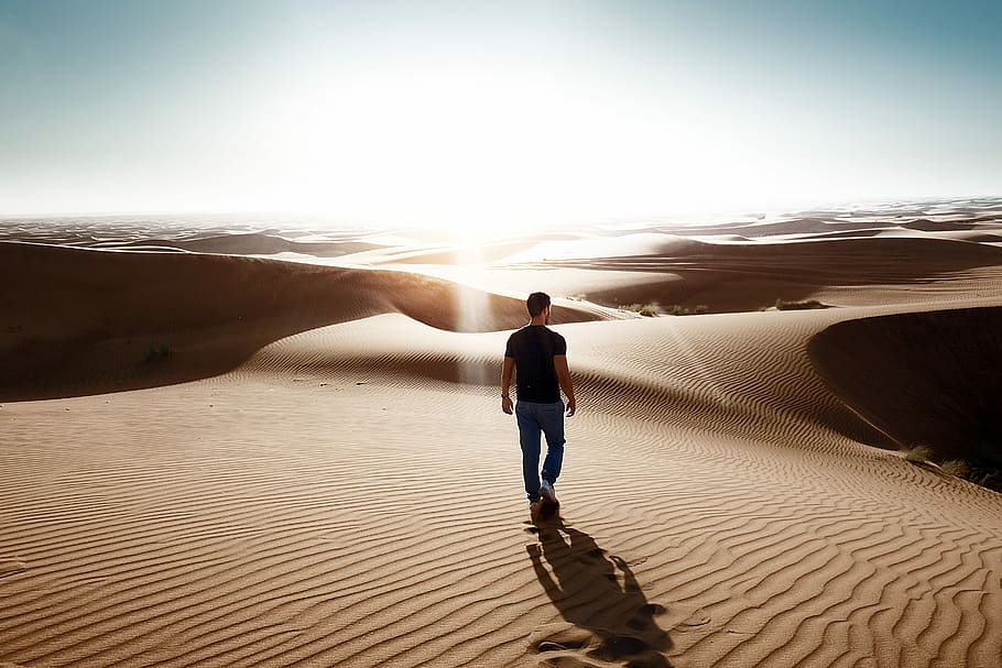 man walking through desert area, man standing on desert field during daytime HD wallpaper