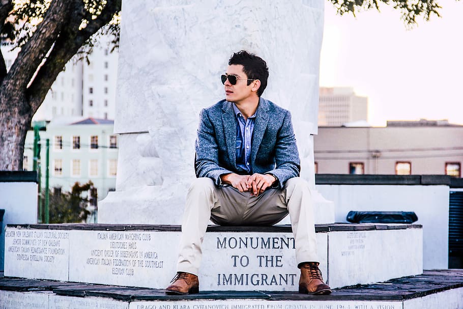 man in blue suit jacket sitting near tree, man looking side sitting on monument HD wallpaper