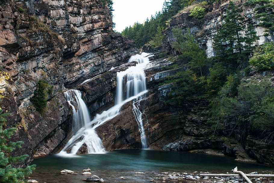waterfalls on rock formations, waterfalls near cliff and tree under clear sky HD wallpaper