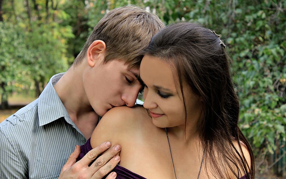 man kissing the shoulder of the woman wearing black dress, girl