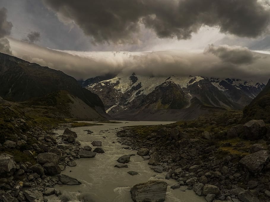 Land of the Long White Cloud, rain clouds above ice-covered rocky mountains with river on base HD wallpaper