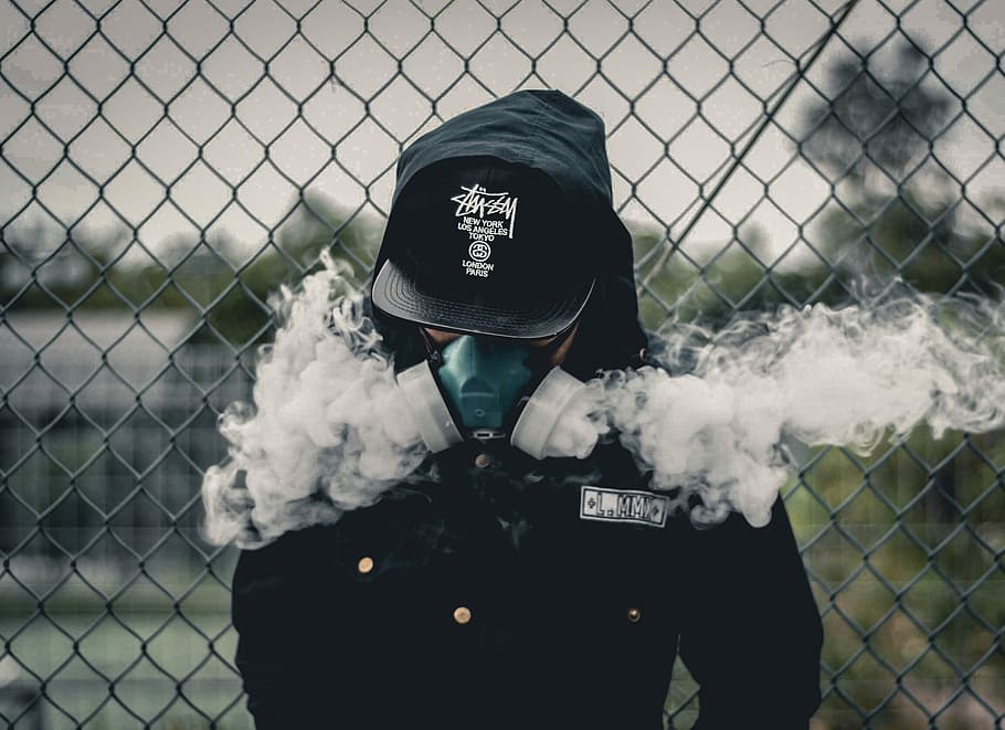 person wearing black fitted cap, shallow focus photography of person wearing green and white bong mask, black cap, and hooded jacket leaning on gray steel cyclone fence, HD wallpaper