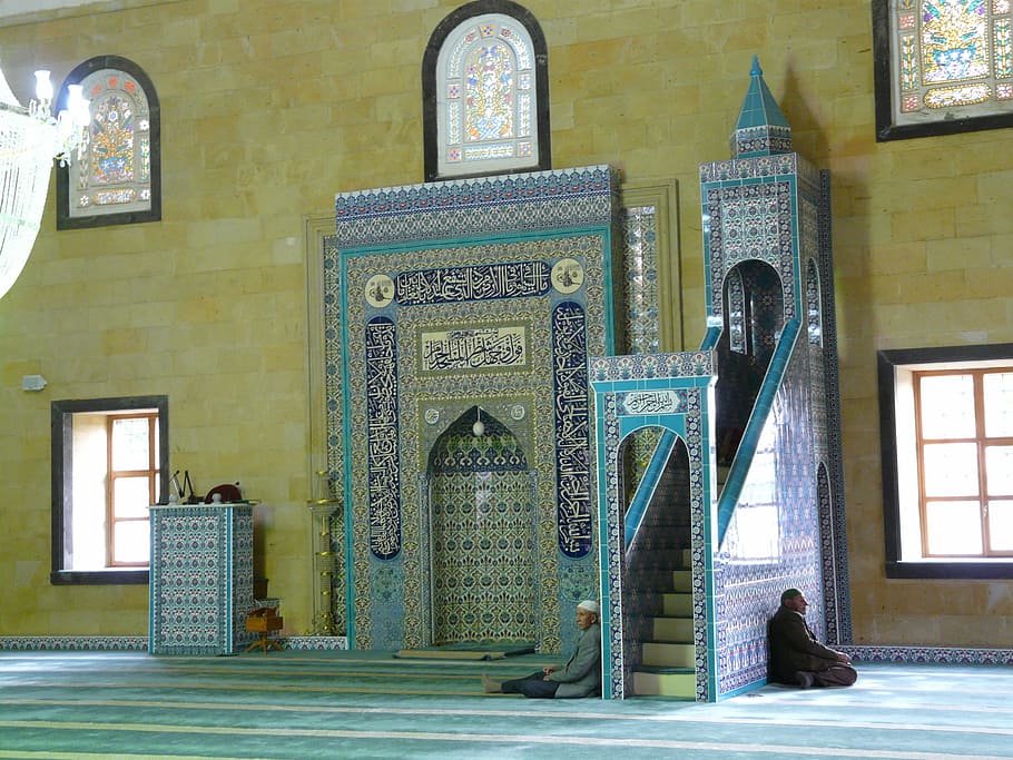 man leaning against wall inside mosque, prayer room, prayer hall