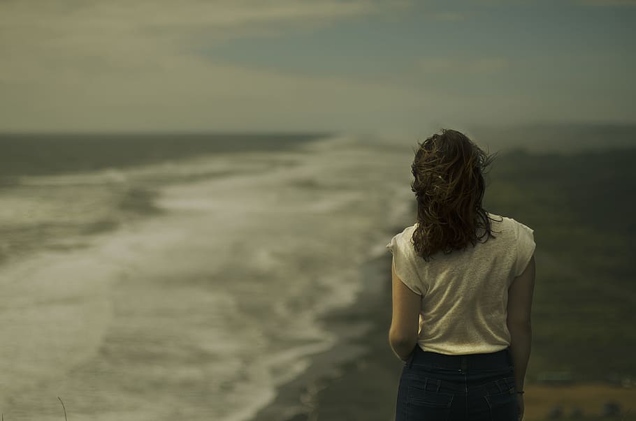 woman standing near seashore, woman in white shirt facing ocean