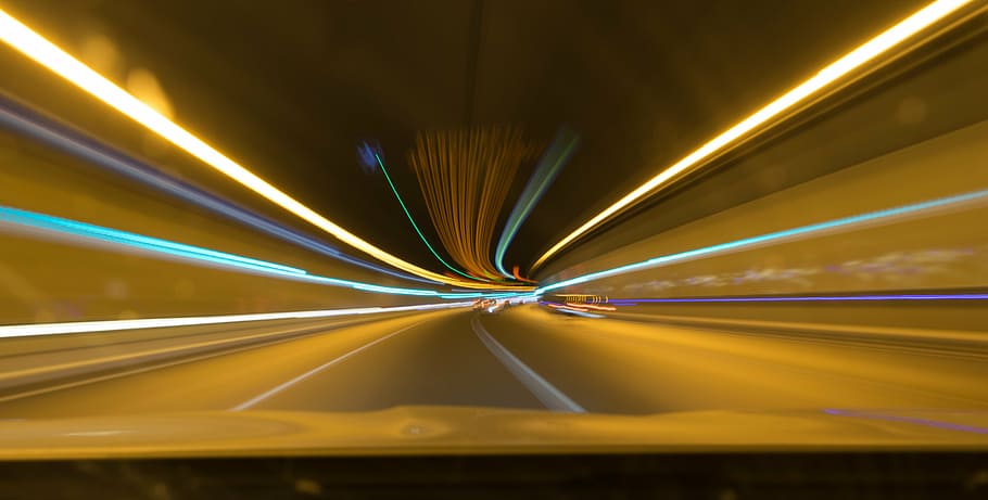 panning photo of tunnel roadway, lights, stelae, color, speed