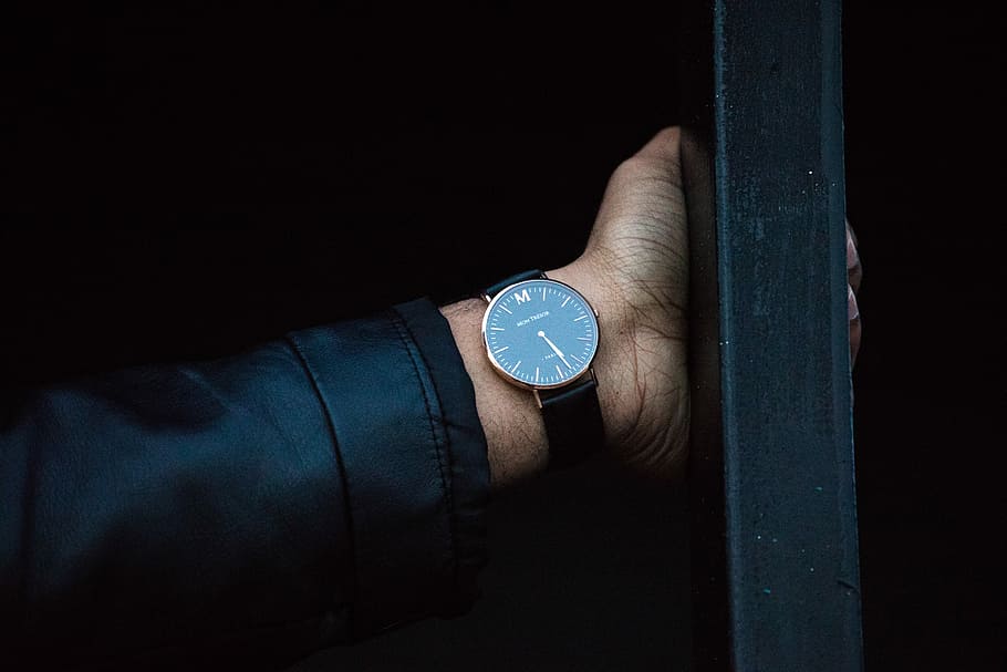 person wearing round analog watch with strao, person wearing black suit blazer and round analog watch at 5:28 while holding a post HD wallpaper