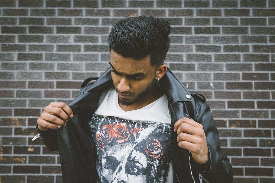 man holding his leather jacket standing near wall during daytime HD wallpaper