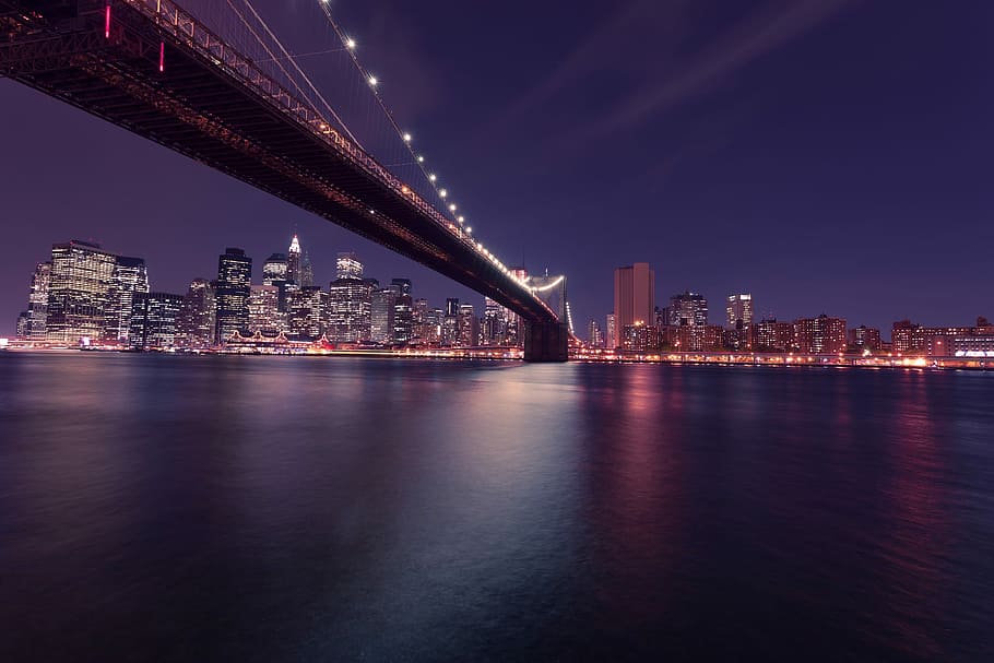 lighted suspension bridge near city buildings during nighttime HD wallpaper