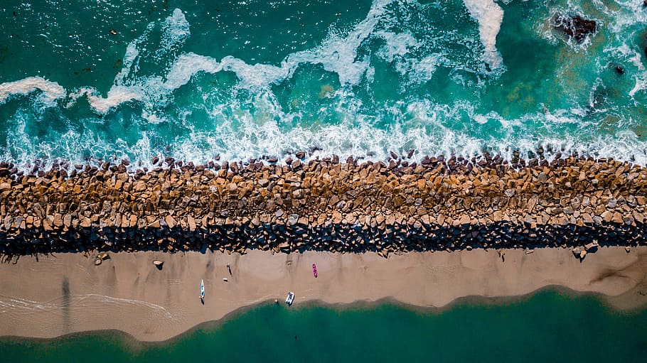 aerial photography of sea near seashore at daytime, water splashing on rocks HD wallpaper