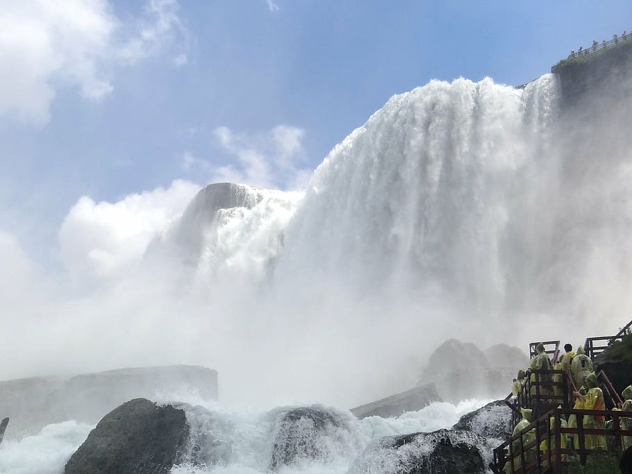 people standing on bridge facing large waterfalls during daytime HD wallpaper