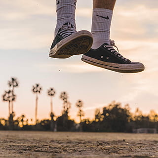 person wearing black low-top sneakers jumping high under white sky, person jumping on top of concrete pavement HD wallpaper