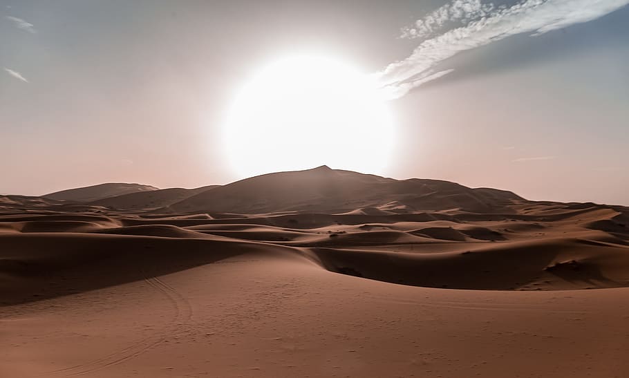 Sun rides over rolling sand dunes of the Sahara Desert, landscape photography of sand at daytime