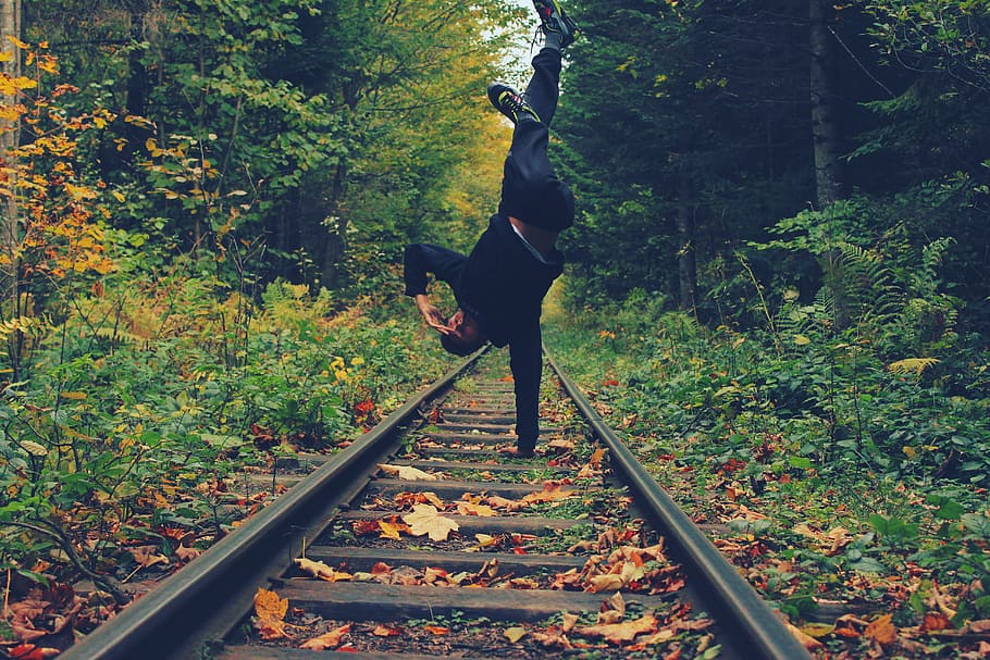 Man Standing With His Right Hand on the Train Rails in Middle of Forest HD wallpaper