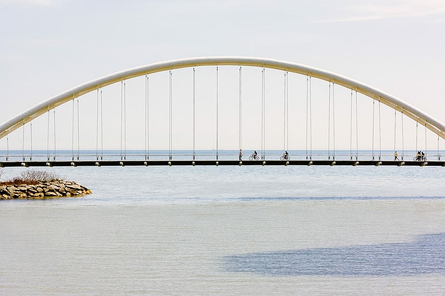 gray bridge above the ocean, person riding bicycle on arch suspension bridge HD wallpaper