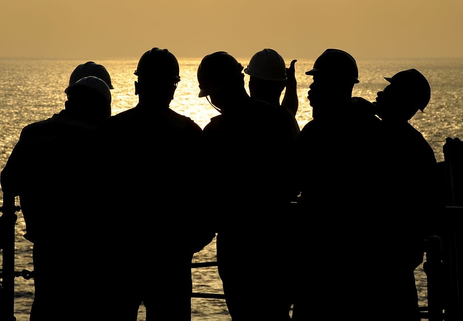 silhouette photography of six men standing on dock beside calm body of water