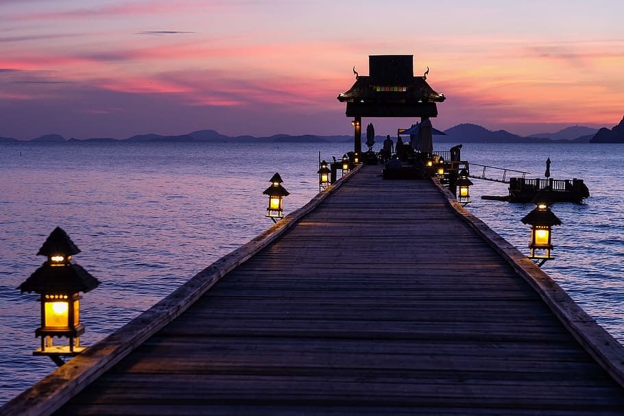 dock in the middle of ocean, brown wooden dock with lanterns in middle of body of water HD wallpaper