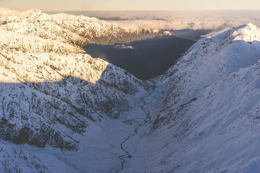 bird's-eye view of mountain covered with snow, bird's-eye photography of mountain near body of water HD wallpaper