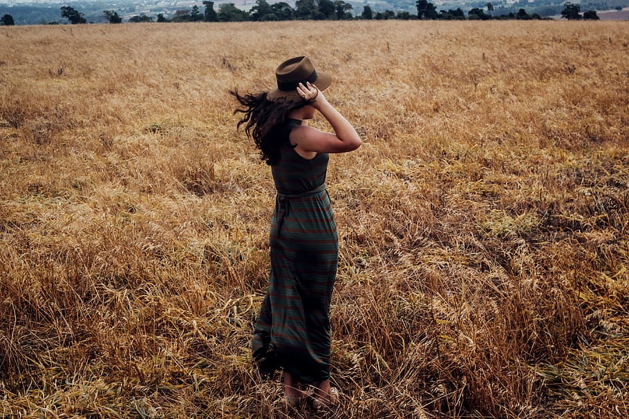 Woman wearing a hat standing in a wheat field, people, fashion
