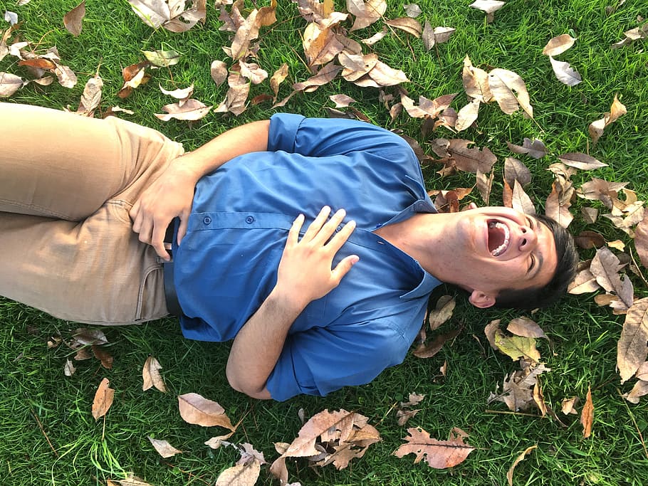 laughing man wearing blue dress shirt lying on green grass lawn, HD wallpaper