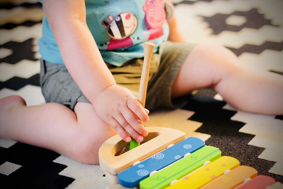 child plating on carpet, child squatting on floor playing xylophone