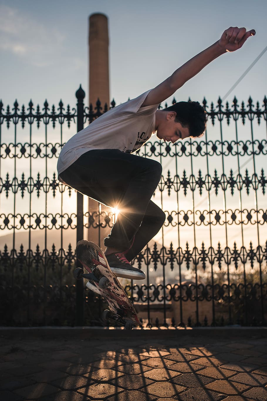 man doing skateboard trick near black steel fence during daytime, man doing tricks on the skateboard near metal fence