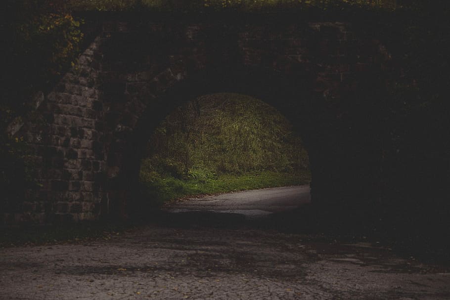 gray road in black concrete brick tunnel, shallow focus photography of pathway in between rock formation HD wallpaper