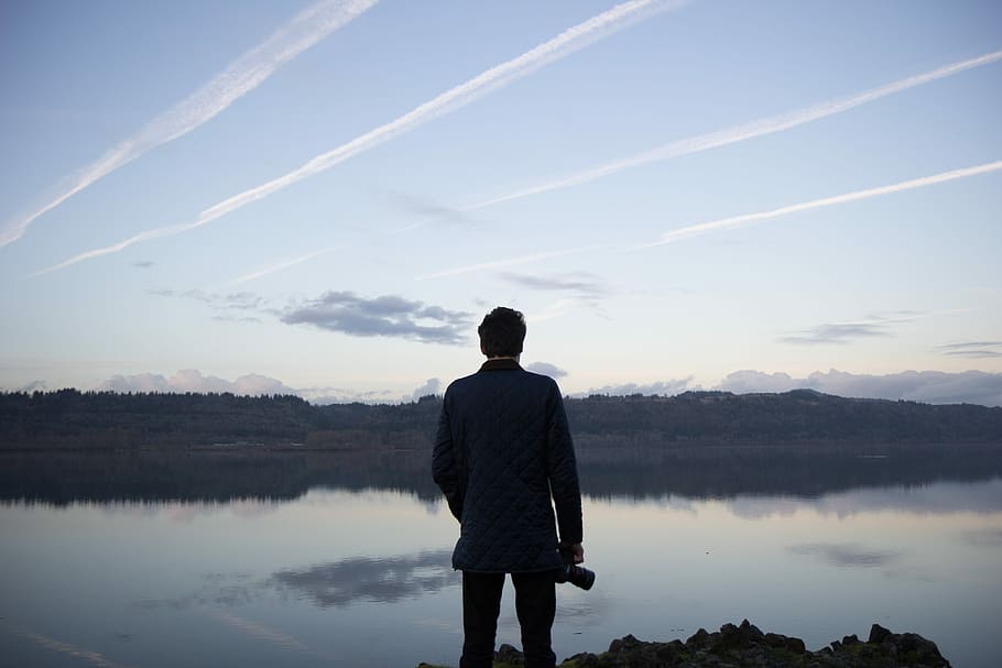 man standing watch calm body of water during daytime, time Of Day HD wallpaper