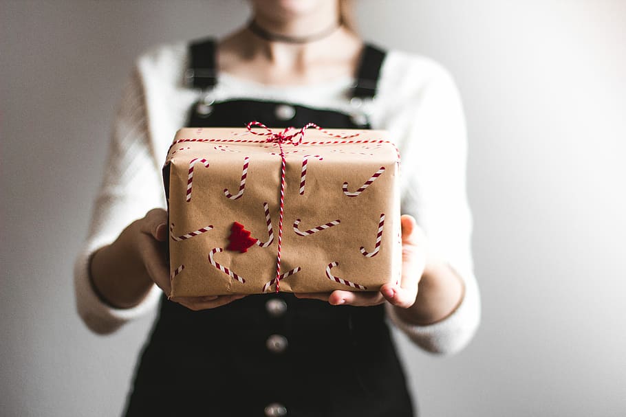 tilt-shift lens photography of woman holding candy cane-print gift box in a well-lit room, person holding brown gift box HD wallpaper
