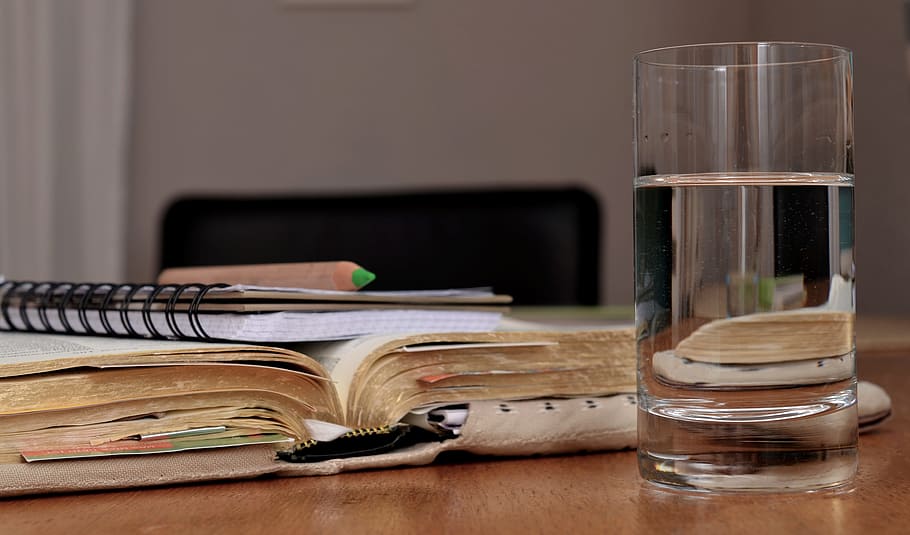 water in clear drinking glass and title book on table, learn HD wallpaper