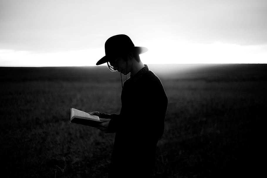 grayscale photography of a person in black dress shirt wearing black hat reading a book HD wallpaper